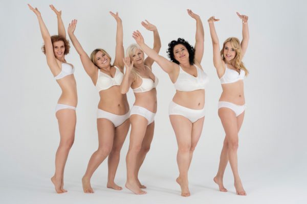 Πέντε γυναίκες ποζάρουν χαρούμενες με τα χέρια ψηλά φορώντας λευκά εσώρουχα.