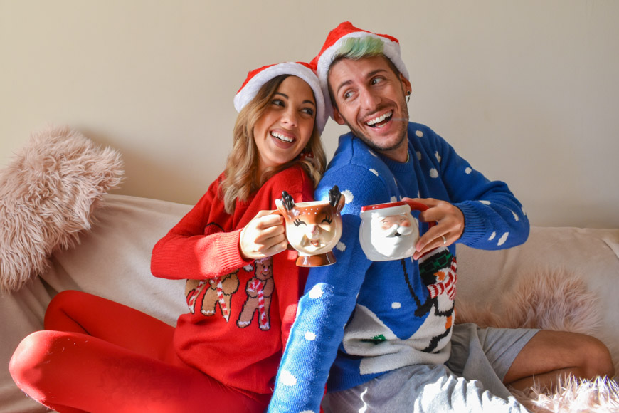 Άνδρας και γυναίκα με γιορτινές φόρμες κρατούν κούπες, μια καλή επιλογή για Χριστουγεννιάτικα δώρα για την οικογένεια.